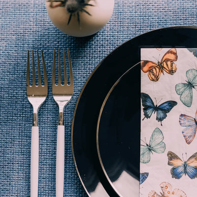 plastic black with gold rim dinner plate and salad plate with colorful butterfly guest towel napkin and white with gold two tone plastic forks 
